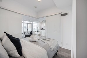 Ein modernes Schlafzimmer mit einem großen Bett, einem Schreibtisch und Blick auf die Stadt durch das Fenster.