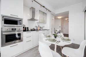 Eine moderne Küche mit integrierten Geräten, eine Essecke mit weißen Stühlen und einem klaren, minimalistischen Design.