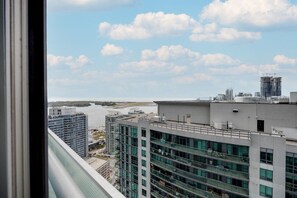 A high-rise building with multiple floors, large windows, and a view of a river and other buildings in the distance. - Scenic Cityscape 1BR Condo with CN Tower View (Toronto)
