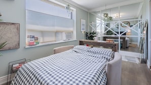 A bedroom with a bed, a window with blinds, a bedside table, and a mirror. - Cozy 1BR Toronto Stay Near Transit & Dining (Toronto)