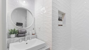 A bathroom with a white sink, a mirror, a potted plant, and toiletries on a shelf. - Cozy 1BR Toronto Stay Near Transit & Dining (Toronto)