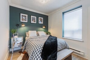 A bedroom with a bed, bedside tables, wall art, and a window with blinds. - Cozy 1BR Toronto Stay Near Transit & Dining (Toronto)