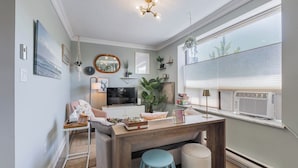 A modern living room with a television, seating area, and a large window with blinds. - Cozy 1BR Toronto Stay Near Transit & Dining (Toronto)