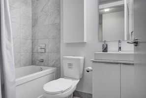 Une salle de bain équipée d’une baignoire, de toilettes et d’un meuble-lavabo avec un miroir.