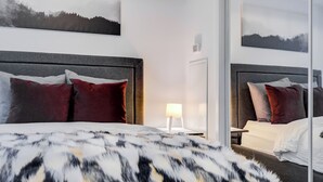 A hotel room with a large bed, two bedside tables, a nightstand, a lamp, and a mirror. - Stylish 1Bed Den Unit in the heart of Dt (Toronto)