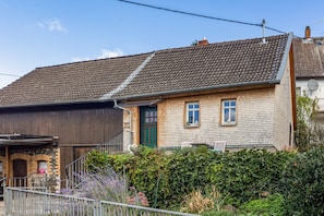 A two-story house with a tiled roof, a green door, and a small window.