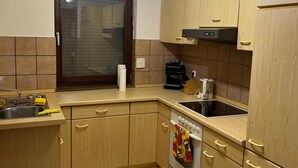 A kitchen with wooden cabinets, a window, a sink, and a stove. - Holiday Home 'Ferienhaus Im Grünen Mit Garten' with Private Garden and Wi-Fi (Schotten)