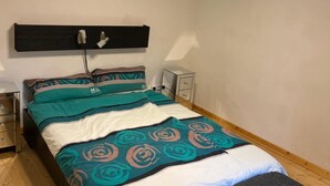 A bedroom with a bed, bedside tables, a bench, and a ceiling light fixture. - Holiday Home 'Ferienhaus Im Grünen Mit Garten' with Private Garden and Wi-Fi (Schotten)
