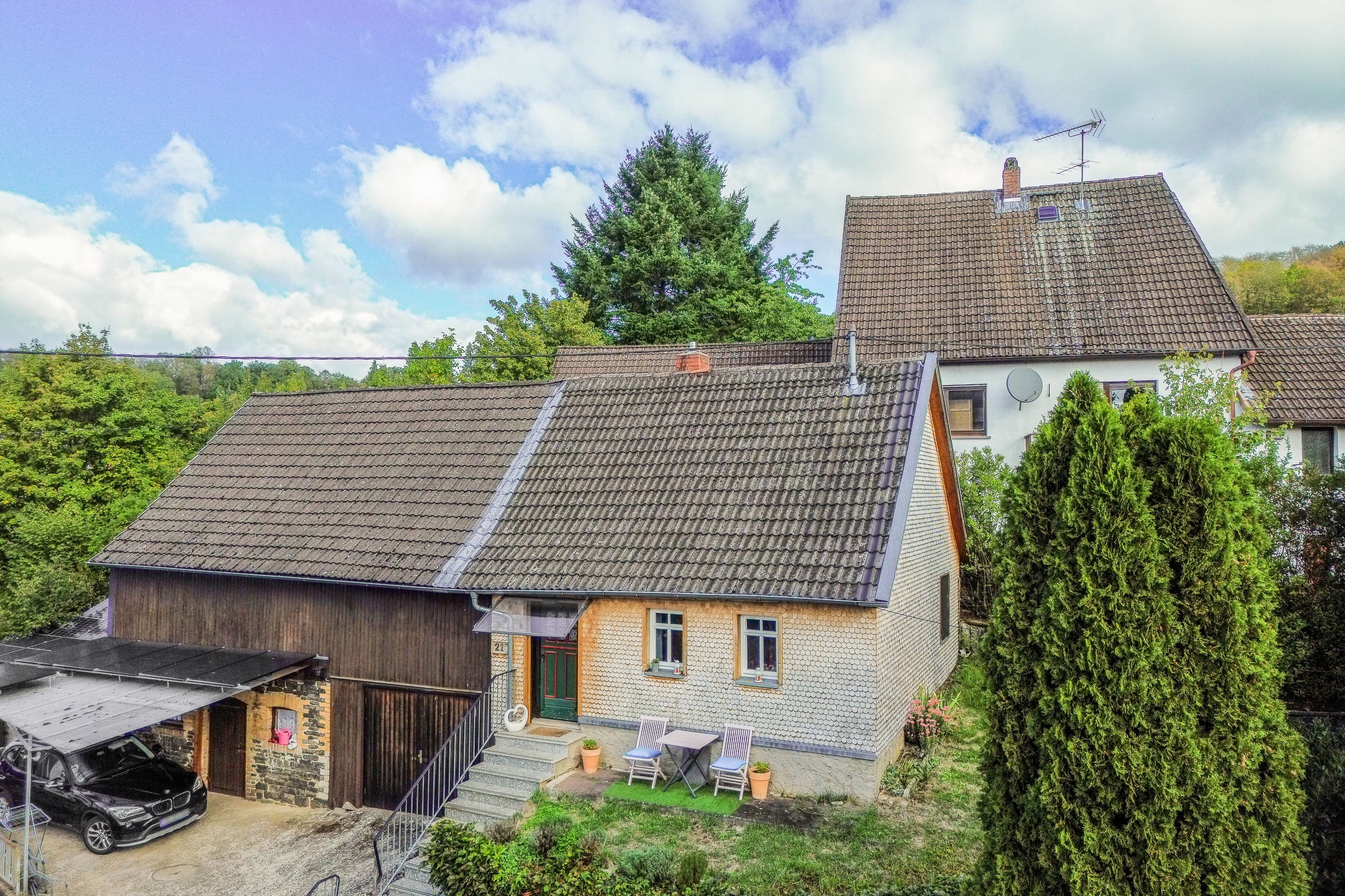 A two-story house with a sloped roof, a visible chimney, and a satellite dish.