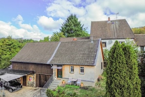 A two-story house with a sloped roof, a visible chimney, and a satellite dish.