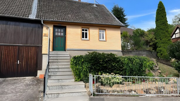 A two-story house with a green door, a small window, and a visible number '21' on the wall. - Holiday Home 'Ferienhaus Im Grünen Mit Garten' with Private Garden and Wi-Fi (Schotten)