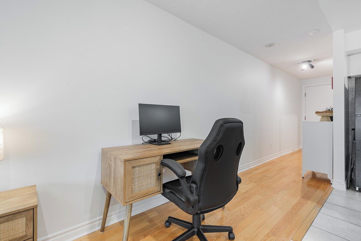 A modern office space with a wooden desk, black office chair, and a computer monitor.