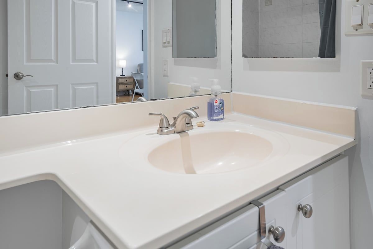 Une salle de bain avec un lavabo blanc, un miroir et une porte.