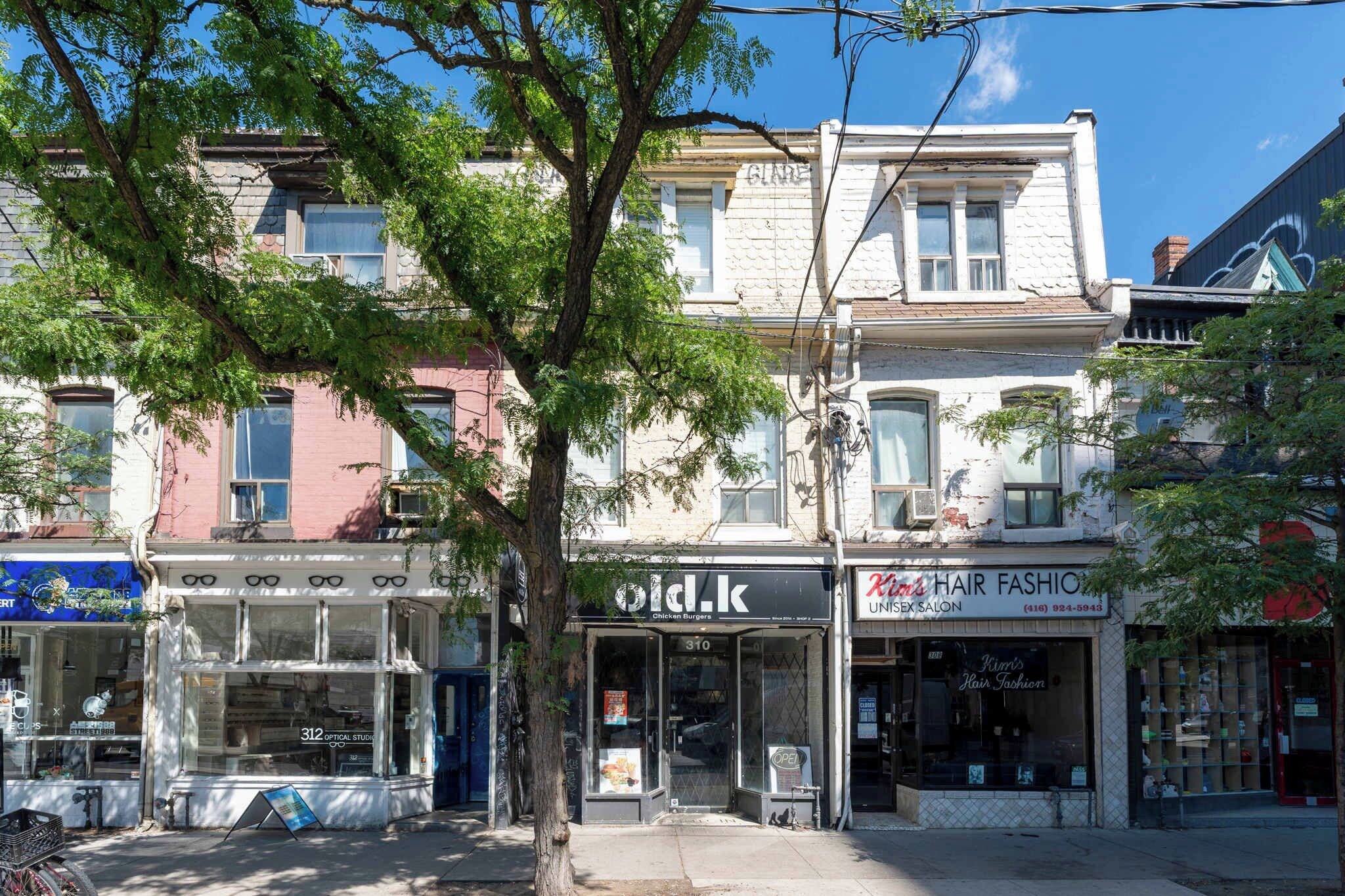 A row of multi-story buildings with various storefronts, including a hair salon and a restaurant.
