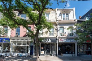 A row of multi-story buildings with various storefronts, including a hair salon and a restaurant. - Spacious 4BR Toronto Stay Near U of T & Downtown (Toronto)