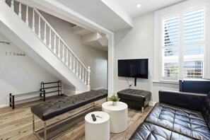 A modern living room with a staircase, a flat-screen TV, leather sofas, and a wooden floor. - Spacious 4BR Toronto Stay Near U of T & Downtown (Toronto)