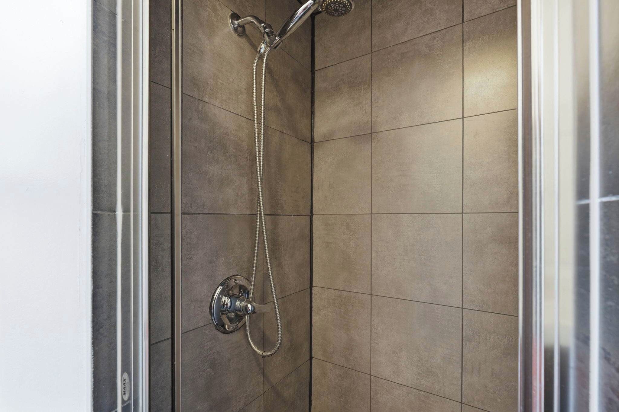 A shower with a handheld showerhead and a fixed wall-mounted showerhead.