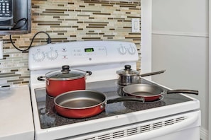 A kitchen with a white stove, two red pots, and a frying pan on the stovetop. - Spacious 4BR Toronto Stay Near U of T & Downtown (Toronto)