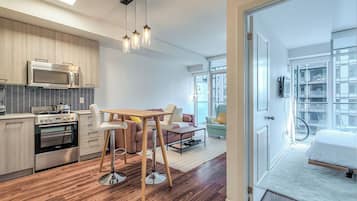 Una cocina moderna con electrodomésticos de acero inoxidable, un comedor con mesa y sillas de madera, y un amplio ventanal que proporciona luz natural.