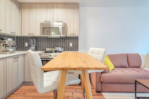 Una cocina moderna con una mesa de madera, sillas blancas, un sofá y un microondas.