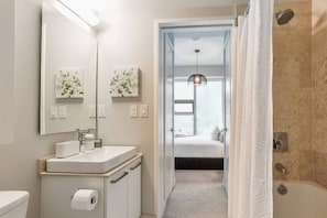 A modern bathroom with a toilet, sink, and shower. - Designer Condo 2BR + 1BA Sleeps 5, Near CN Tower (Toronto)