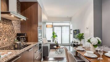 Una cocina moderna con encimeras de granito, estufa integrada y comedor con una mesa lista para dos comensales.