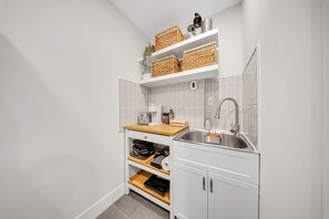 Eine kleine Küche mit weißen Schränken, einer Edelstahl-Spüle und einer Holz Arbeitsplatte.