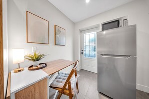 A modern kitchen with a built-in refrigerator, a dining table with chairs, and framed artwork on the wall. - Cozy Studio w/ Fast WiFi, Parking & Workspace (Toronto)