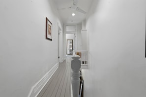 A narrow hallway with white walls, a wooden floor, and a ceiling fan. - Remodeled 2BR Victorian Gem Near Queen West (Toronto)
