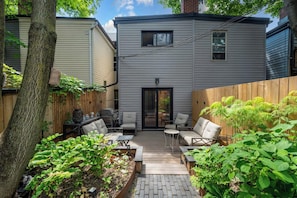 A residential backyard with a patio area, outdoor furniture, and a wooden fence. - Remodeled 2BR Victorian Gem Near Queen West (Toronto)