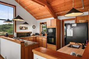 Una cocina moderna con armarios de madera, un refrigerador negro y un horno empotrado.