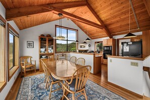 Un comedor amplio con mesa y sillas de madera, una cocina con electrodomésticos modernos y un gran ventanal con vistas al exterior.