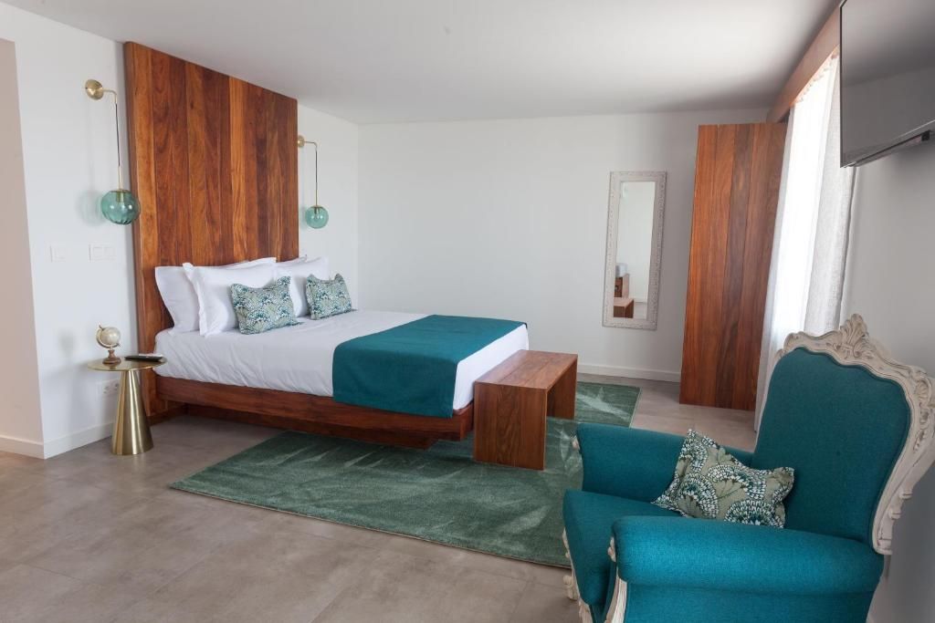 Un dormitorio con cama, mesita de noche, silla y espejo.