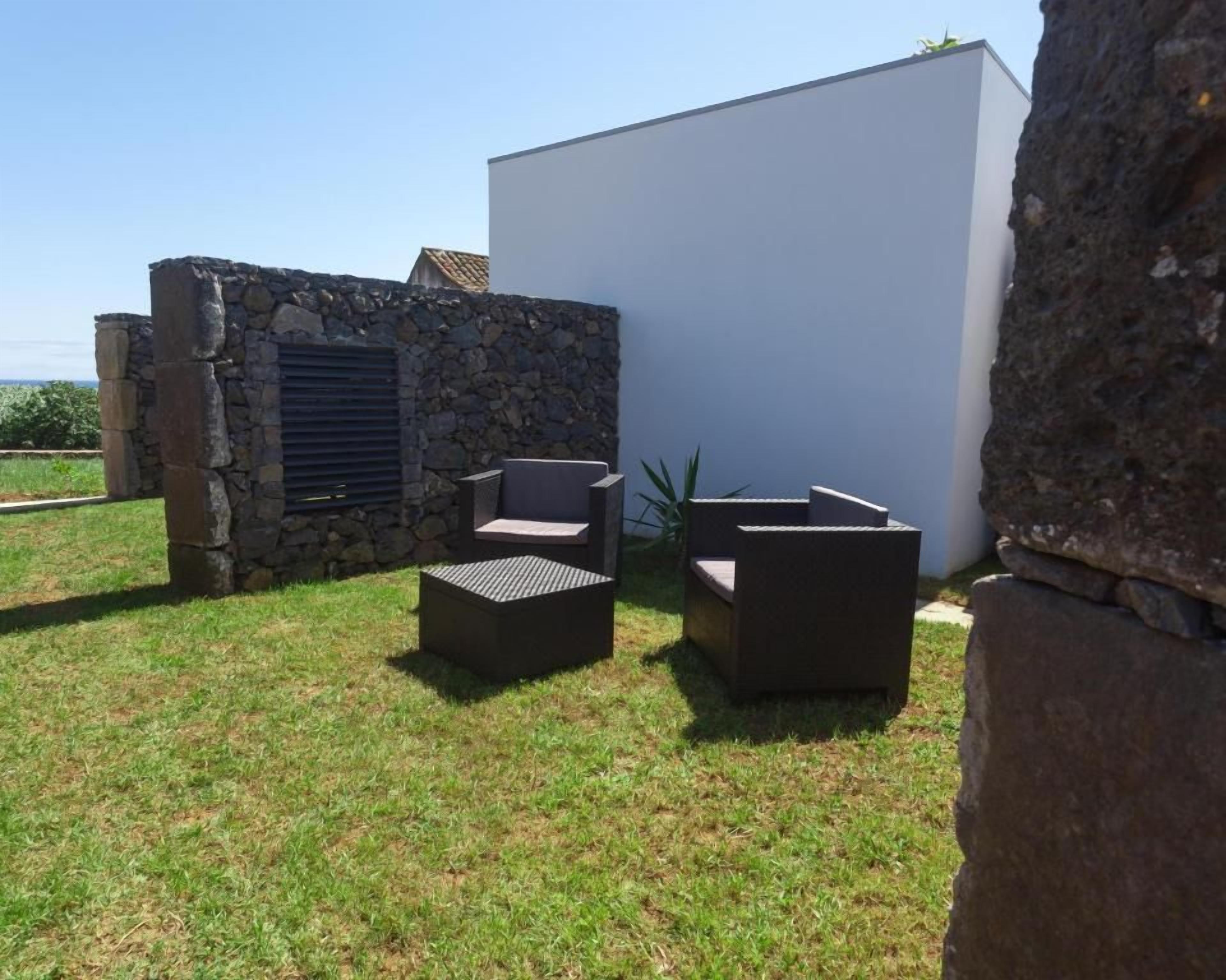 Un espace extérieur aménagé avec des murs en pierre et un bâtiment blanc en arrière-plan.