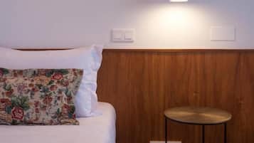 Un dormitorio con cama, mesita de noche, lámpara de pared y toma de corriente.