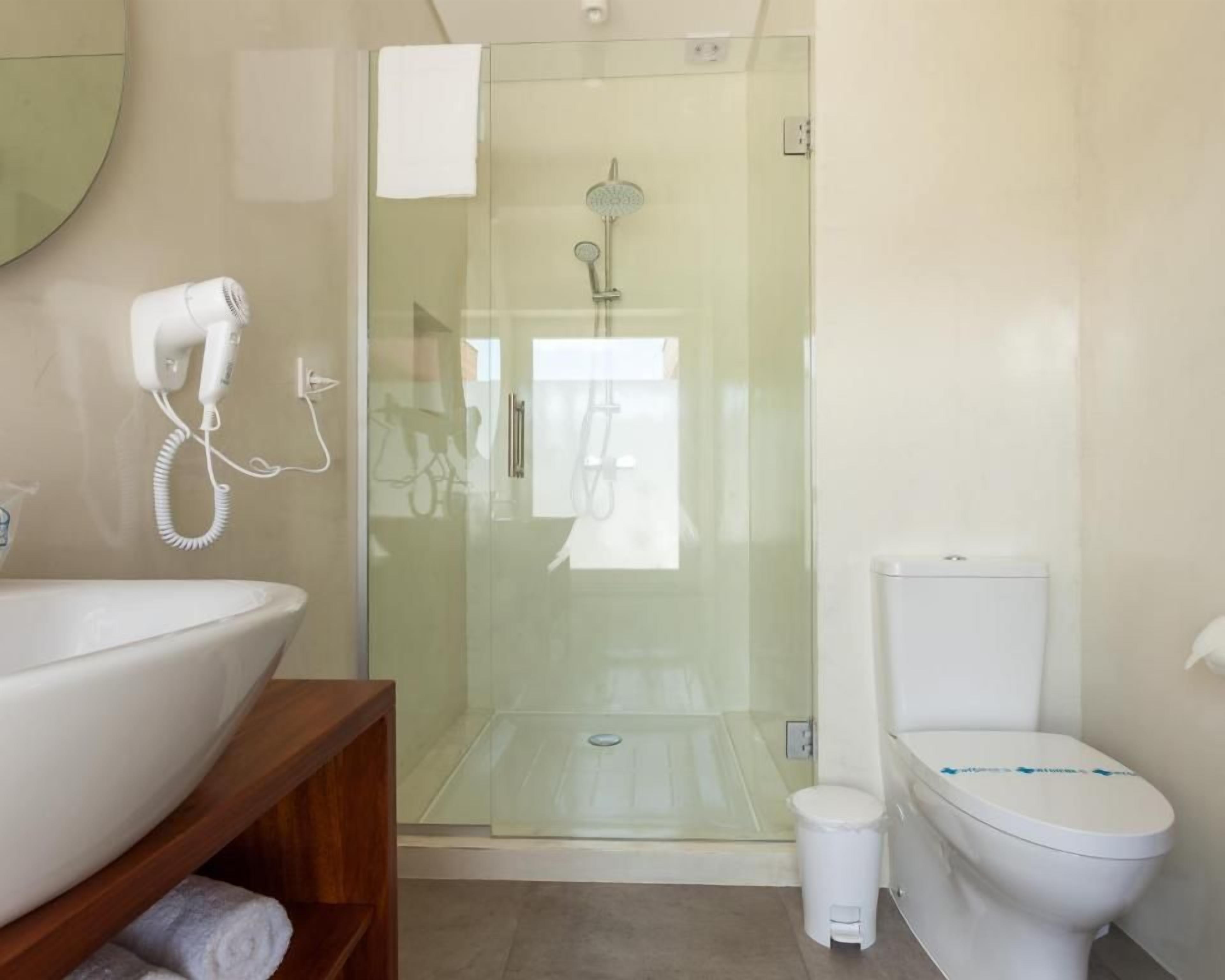 A bathroom with a glass-enclosed shower, a white sink, and a toilet.