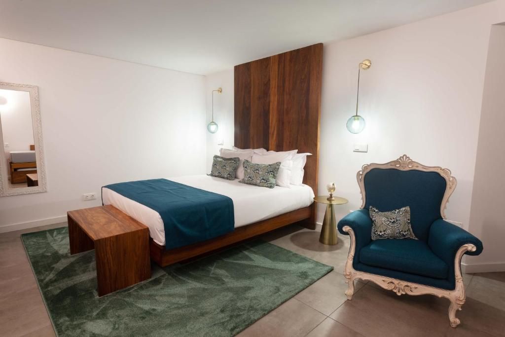 A bedroom with a bed, bedside table, chair, and a mirror.