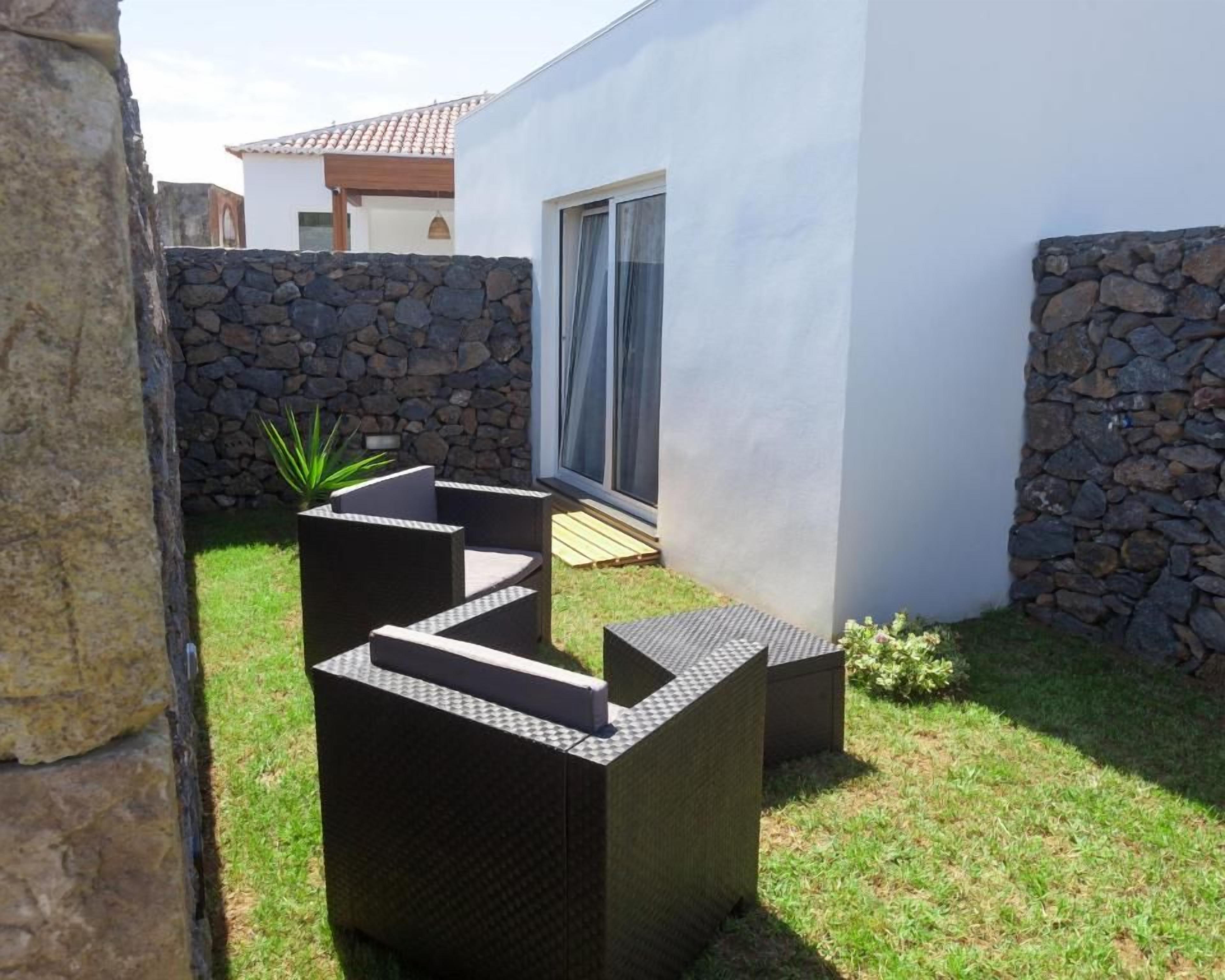 A modern outdoor seating area with a stone wall and a white building in the background.