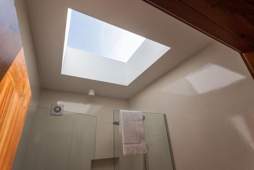 A skylight in a bathroom with a glass shower enclosure and a towel hanging on the door.