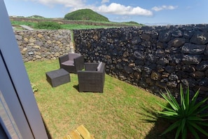 An outdoor seating area with stone walls and a view of hills. - Casa dos Romeiros (SANTA BARBARA)