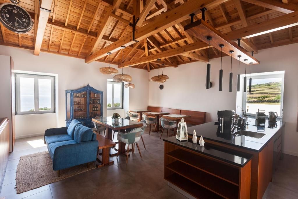 Una cocina moderna con techo de madera, un área de comedor con sillas y sofá, y vistas al exterior a través de una ventana.