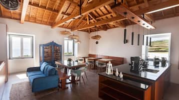 Una cocina moderna con techo de madera, un área de comedor con sillas y sofá, y vistas al exterior a través de una ventana.