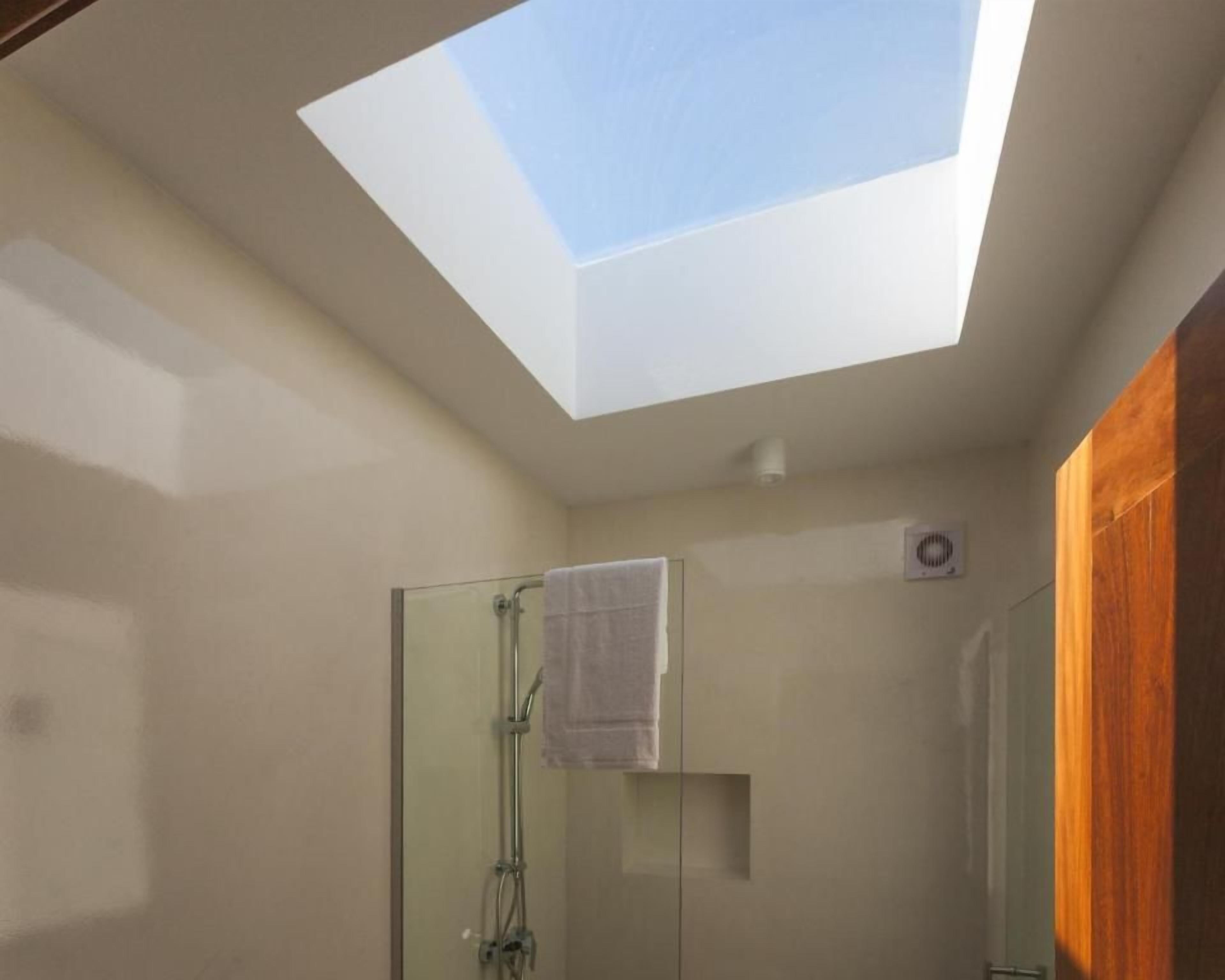 Ein Oberlicht in einem Badezimmer mit Duschkabine aus Glas und einem Handtuch an der Wand.