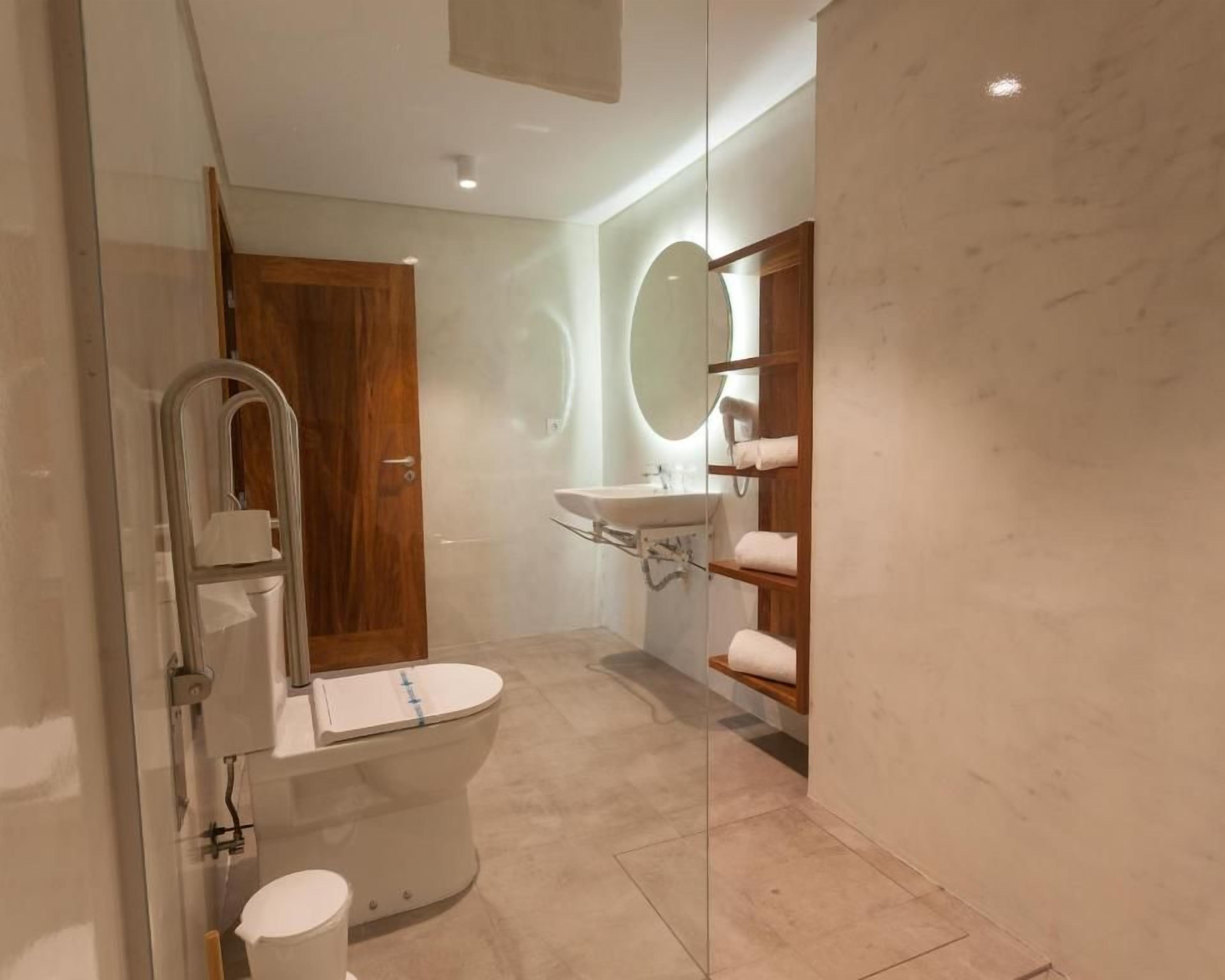 A modern bathroom with a toilet, sink, and glass shower enclosure.