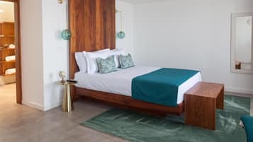 Ein Schlafzimmer mit einem hölzernen Kopfteil, einem Bett mit weißer Bettwäsche und einer türkisblauen Decke, einem Nachttisch mit einem Globus und einem grünen Teppich.
