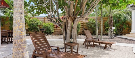 A wooden outdoor seating area with benches and tables, surrounded by trees and a wooden fence.