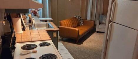 A compact kitchen with a stove, refrigerator, and a dining area with a table and chairs.