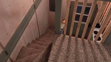 A wooden staircase with a metal handrail and a hanging light fixture.
