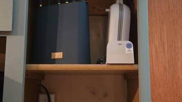 Un mueble con un electrodoméstico azul, un electrodoméstico blanco y toallas dobladas.