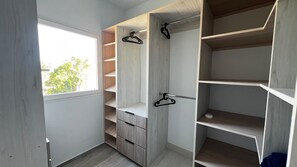 A walk-in closet with open shelves, a hanging rod, and a small cabinet. - Tracadero Lodge Dominicus Penthouse (Dominicus)